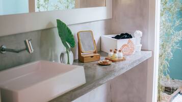 Casa de banho com uma pia grande, um espelho e uma prateleira com produtos de higiene e objetos decorativos.