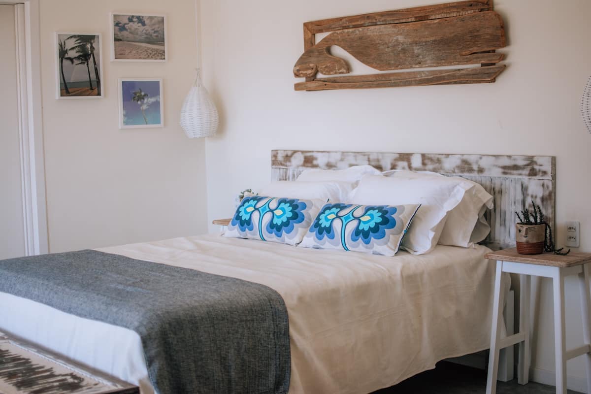 Un dormitorio con cama, mesita de noche y una obra de arte de madera en la pared.