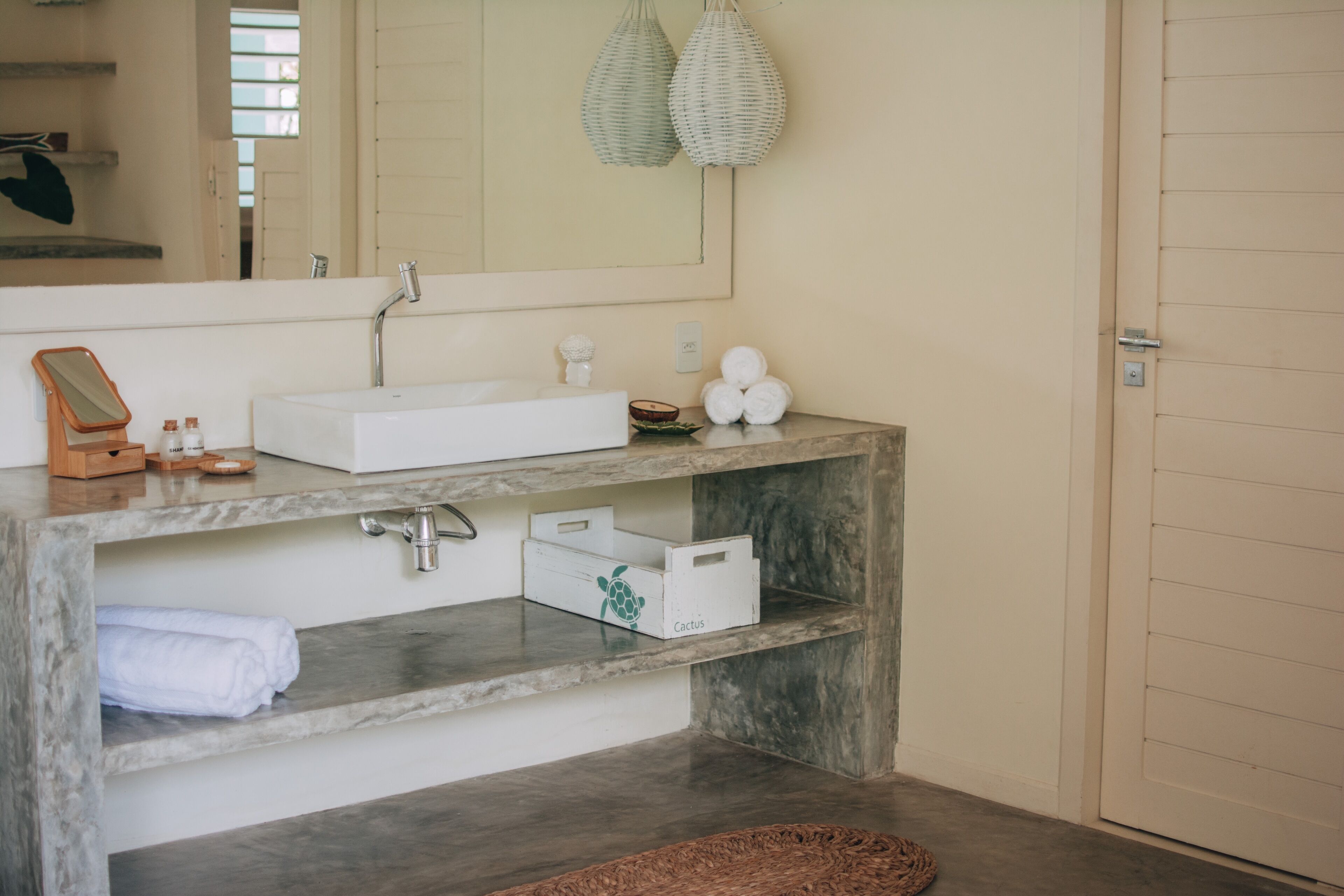 Ein Badezimmer mit Marmorwaschbecken, einem Spiegel, einem Handtuchhalter und einem Holzboden mit Toilettenartikeln.