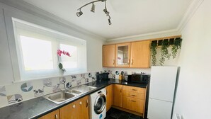 Cocina pequeña equipada con lavadora, lavaplatos y refrigerador.