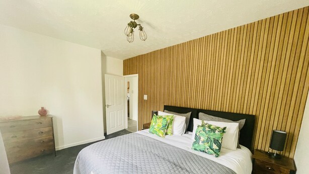 Un dormitorio con cama, pared de paneles de madera y una lámpara en el techo.