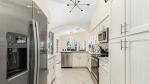 Una cocina moderna con electrodomésticos de acero inoxidable, armarios blancos y una isla central.