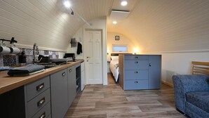 Une cuisine compacte dotée d’un plan de travail en bois, de placards gris et d’une cuisinière intégrée.
