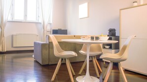 Eine moderne Küche mit einem runden Tisch, vier Stühlen, einem Backofen und einer Kaffeemaschine.