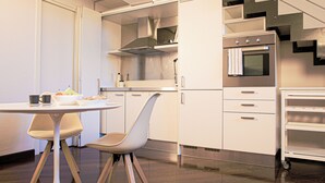 Eine moderne Küche mit weißen Schränken, einer Edelstahl-Dunstabzugshaube, einem eingebauten Backofen und einem kleinen Rollwagen.