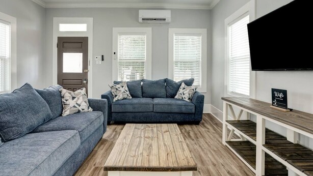 A modern living room with two sofas, a coffee table, and a TV on a white wall.