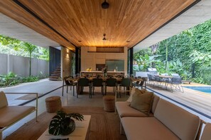 A modern interior with a dining area, kitchen, and a view of a swimming pool.