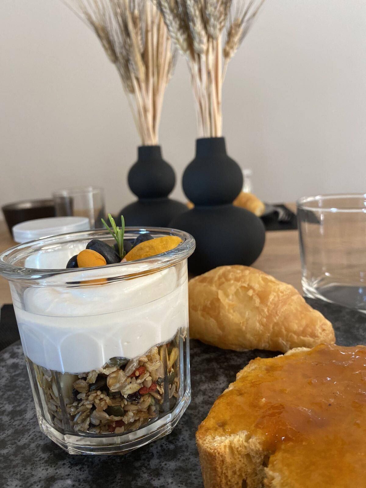 Un postre en vaso, un pastel y una botella de agua sobre una mesa.