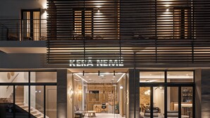 A modern hotel entrance with a glass facade, a visible reception desk, and a staircase leading to the upper floor. - Kera Neme (Nemea)