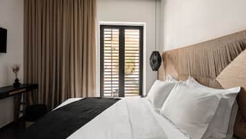 A hotel room with a bed, a desk, a chair, a window with blinds, and a hanging light fixture.