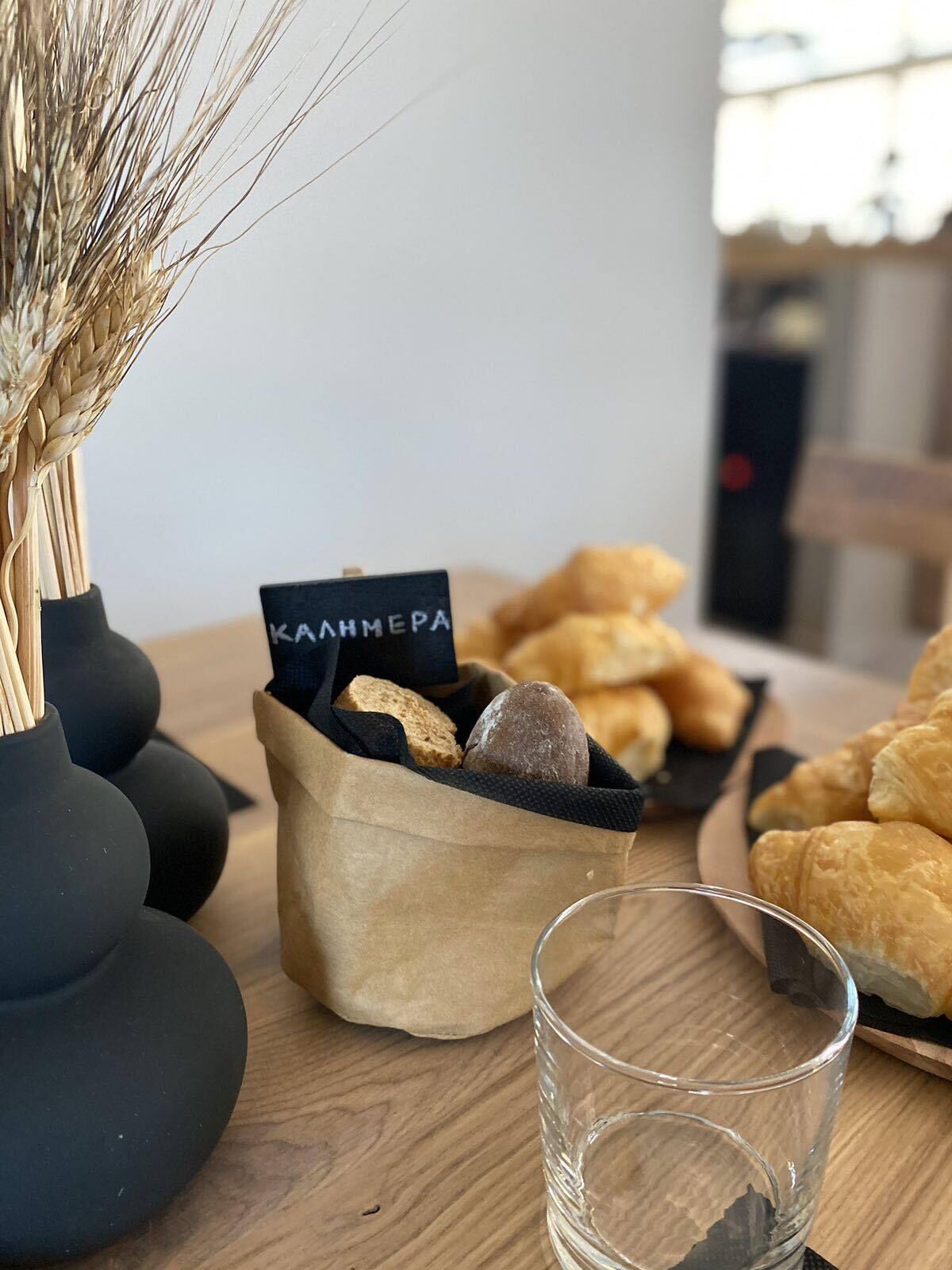 A table with a paper bag containing bread and a glass of water.