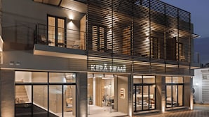 A modern hotel with a glass facade, a visible dining area, and a staircase leading to the entrance. - Kera Neme (Nemea)