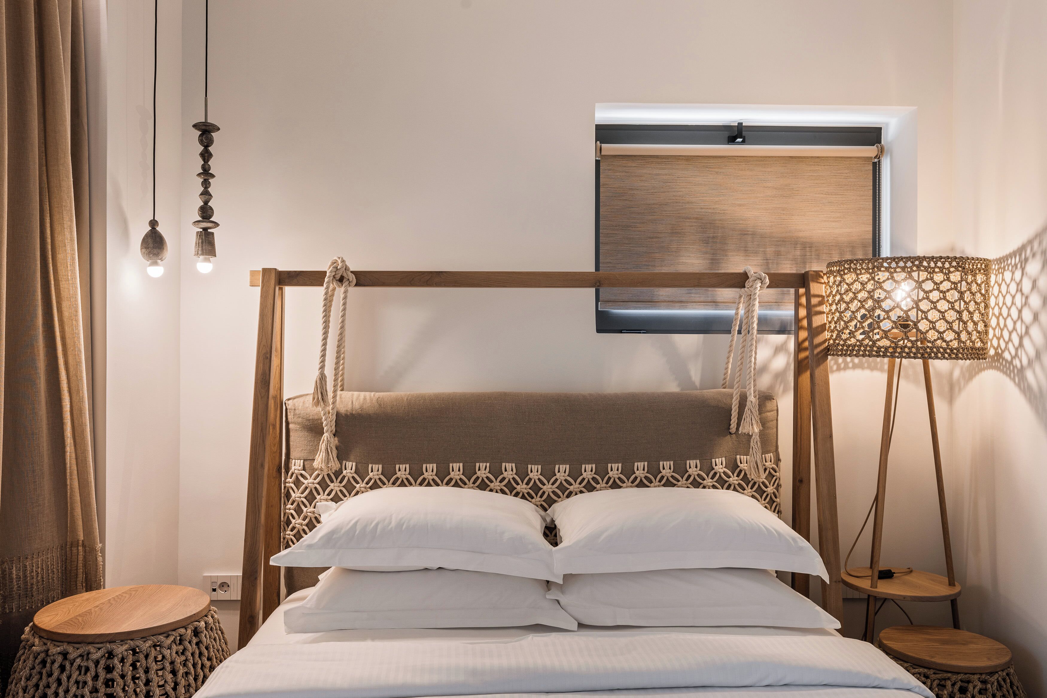 A bed with a wooden frame, white bedding, and a hanging light fixture.