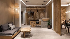 A modern interior with a sofa, round wooden table, stone wall, and wooden partitions. - Kera Neme (Nemea)