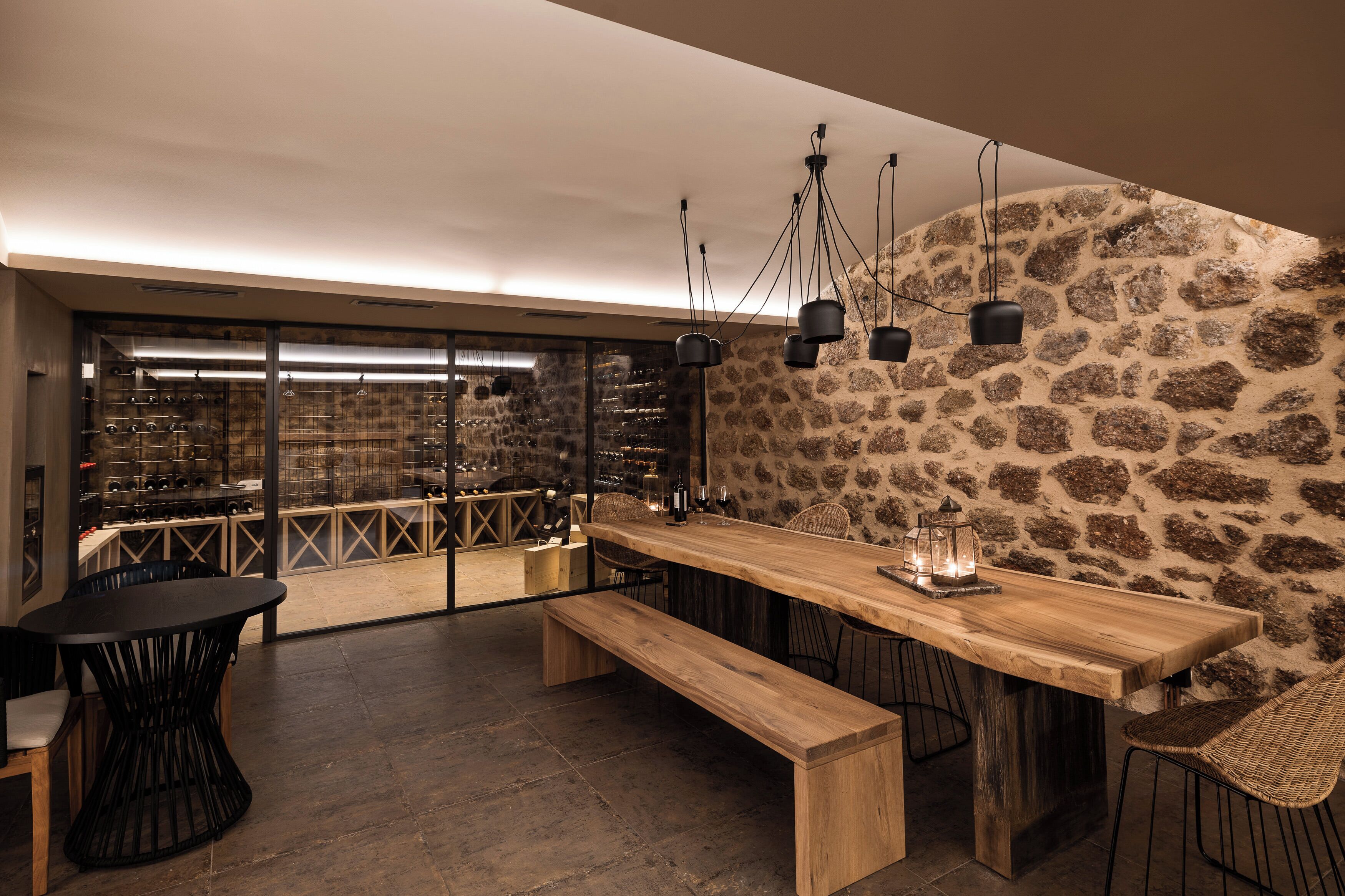 Un área de bar moderna con una larga mesa de madera, sillas negras y lámparas colgantes.