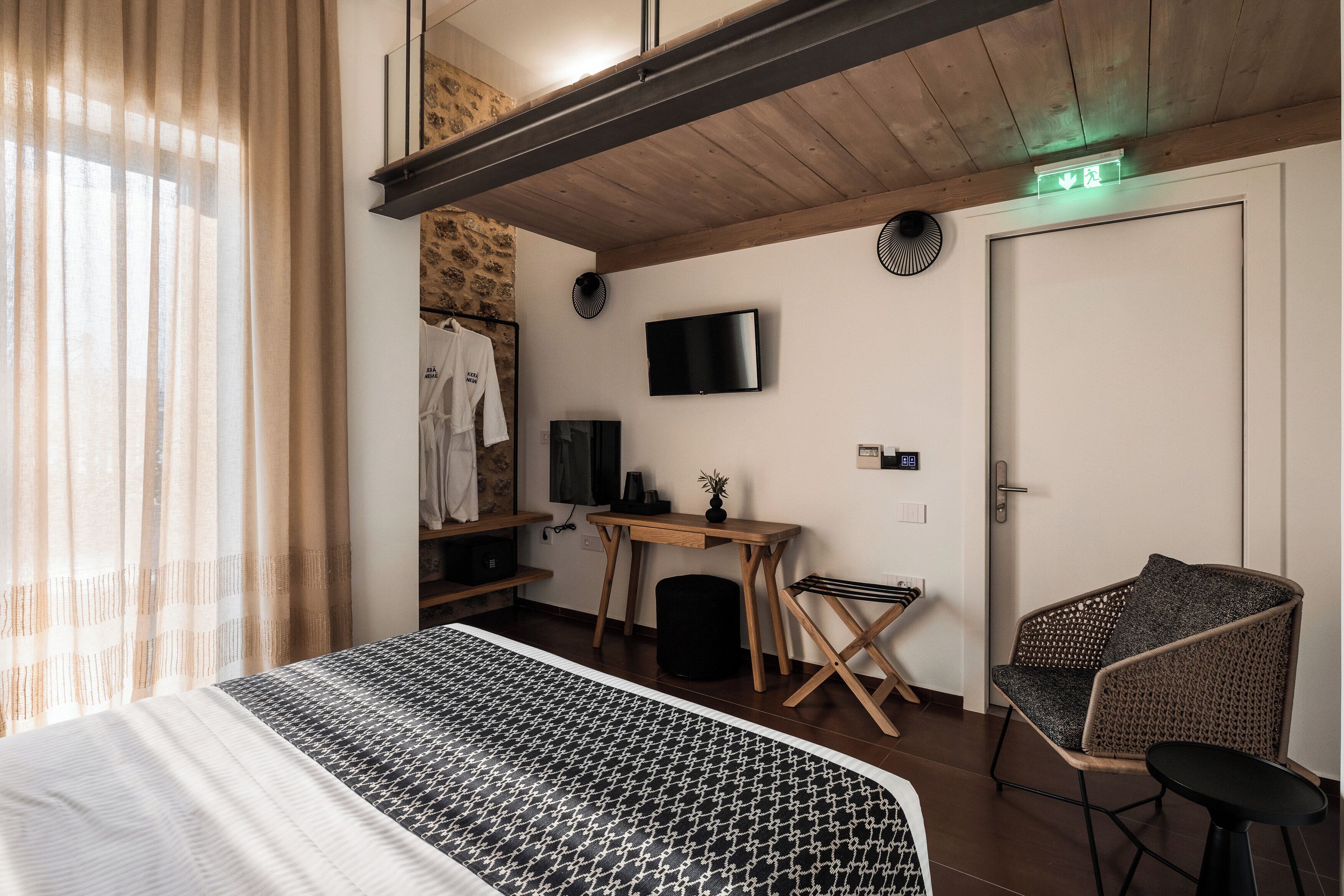 A hotel room with a bed, a desk, a TV, a chair, and a wardrobe.