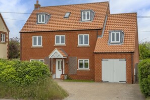 A two-story brick house with a tiled roof, a front door, and a garage.