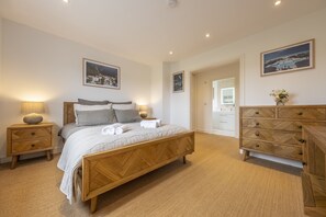 A bedroom with a wooden bed, bedside tables, a dresser, and framed pictures on the walls.