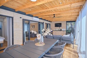 Ein modernes Interieur mit Holzbalkendecke, einem Esstisch mit Stühlen, einer Couch und einer Küchenzeile.