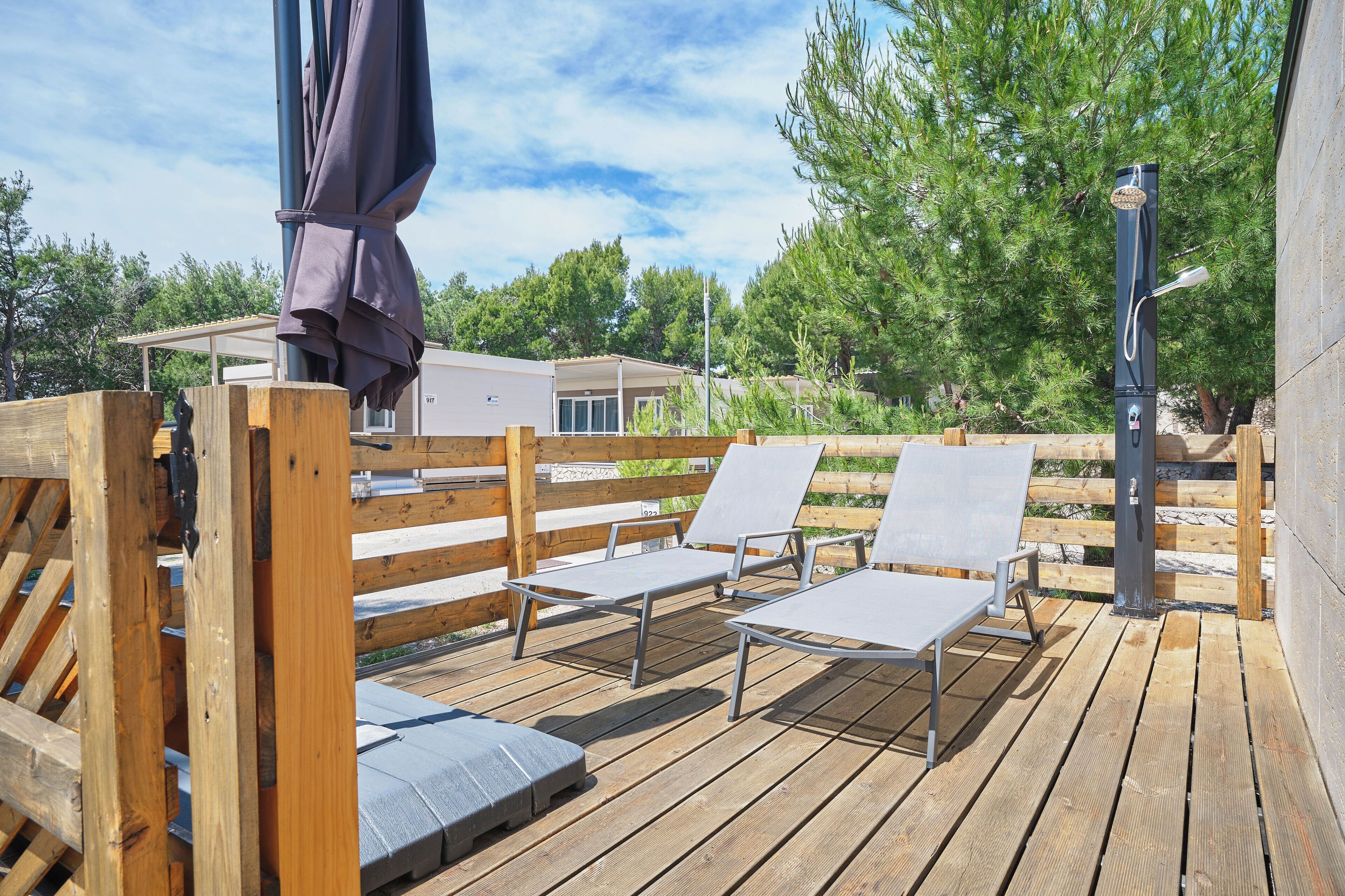 A wooden deck with lounge chairs and a ceiling fan.