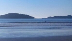 A beach with a clear sky and calm water. - Condomínio Veneza (Ubatuba)