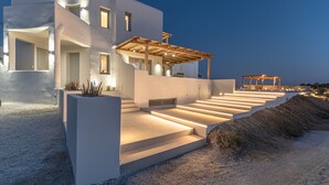 A modern white building with a covered outdoor area and steps leading to a terrace.