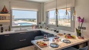 A modern kitchen with a large island, a dining area with a view of the pool, and a large window overlooking the landscape.