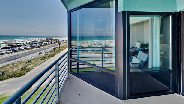 Un balcon donnant sur la plage et les voitures garées.