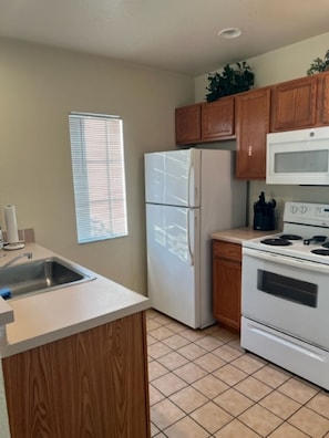 A kitchen with wooden cabinets, a refrigerator, a microwave, and a stove.