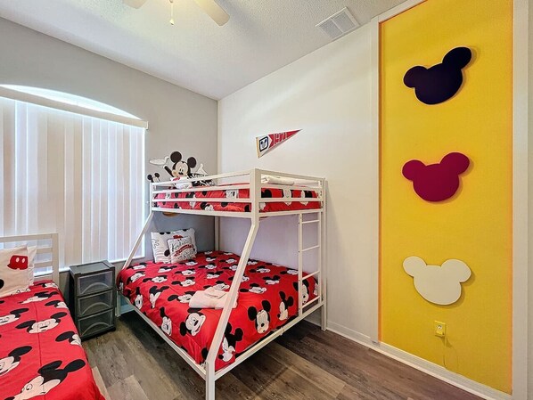 A bunk bed room with Mickey Mouse themed bedding, a flag, and wall decorations.