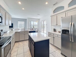 A modern kitchen with a central island, stainless steel appliances, and a large window providing natural light.