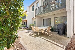 A patio with a table and chairs, a grill, and a balcony. - Oceanfront, 4 BR/5 BA, EV Charging, Super Stylish (Hilton Head Island)