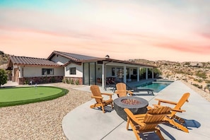 A house with a swimming pool, outdoor seating, and a well-maintained lawn.