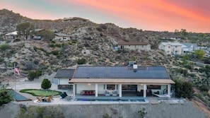 A house with a pool, patio furniture, and solar panels.
