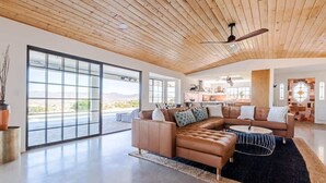 A spacious living area with a large sectional sofa, a round coffee table, and a ceiling fan.