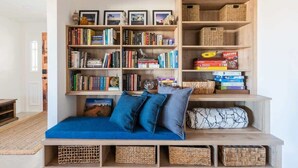 A cozy reading nook with a blue sofa, a bookshelf filled with books, and wicker baskets.
