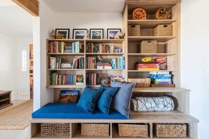 A cozy reading nook with a blue sofa, a bookshelf filled with books, and wicker baskets.