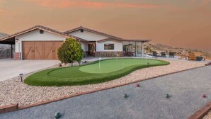 A house with a garage, a well-maintained lawn, and a putting green.