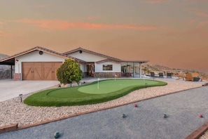 A house with a garage, a well-maintained lawn, and a putting green.