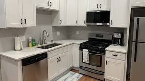 A modern kitchen with white cabinets, stainless steel appliances, and a dishwasher.
