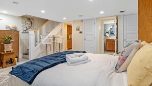 Een slaapkamer met een bed, een trap, een badkamer en een keukenhoek.