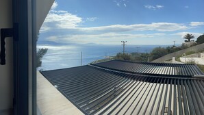 Ein modernes Gebäude mit geneigtem Dach und Blick auf das Meer und ferne Berge.