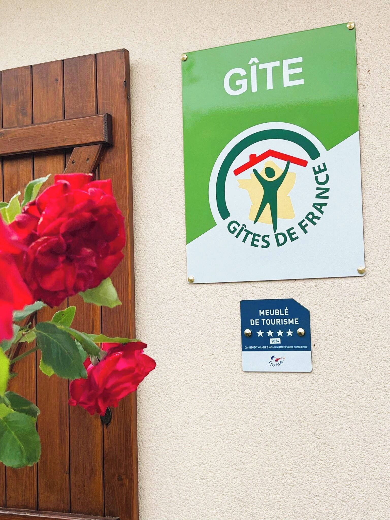 En vägg med en skylt där det står ”GÎTE GÎTES DE FRANCE” och en blå plakett under.