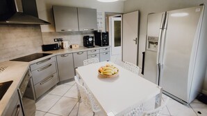 Eine moderne Küche mit weißem Arbeitsplatz, Edelstahlgeräten und einer zentralen Kochinsel mit Obstschale.