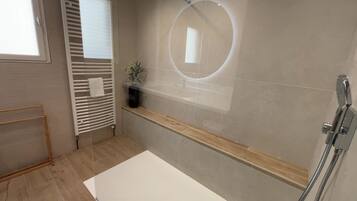 Ein modernes Badezimmer mit einer Badewanne, einem Handtuchhalter, einem Blumentopf und einem Spiegel.