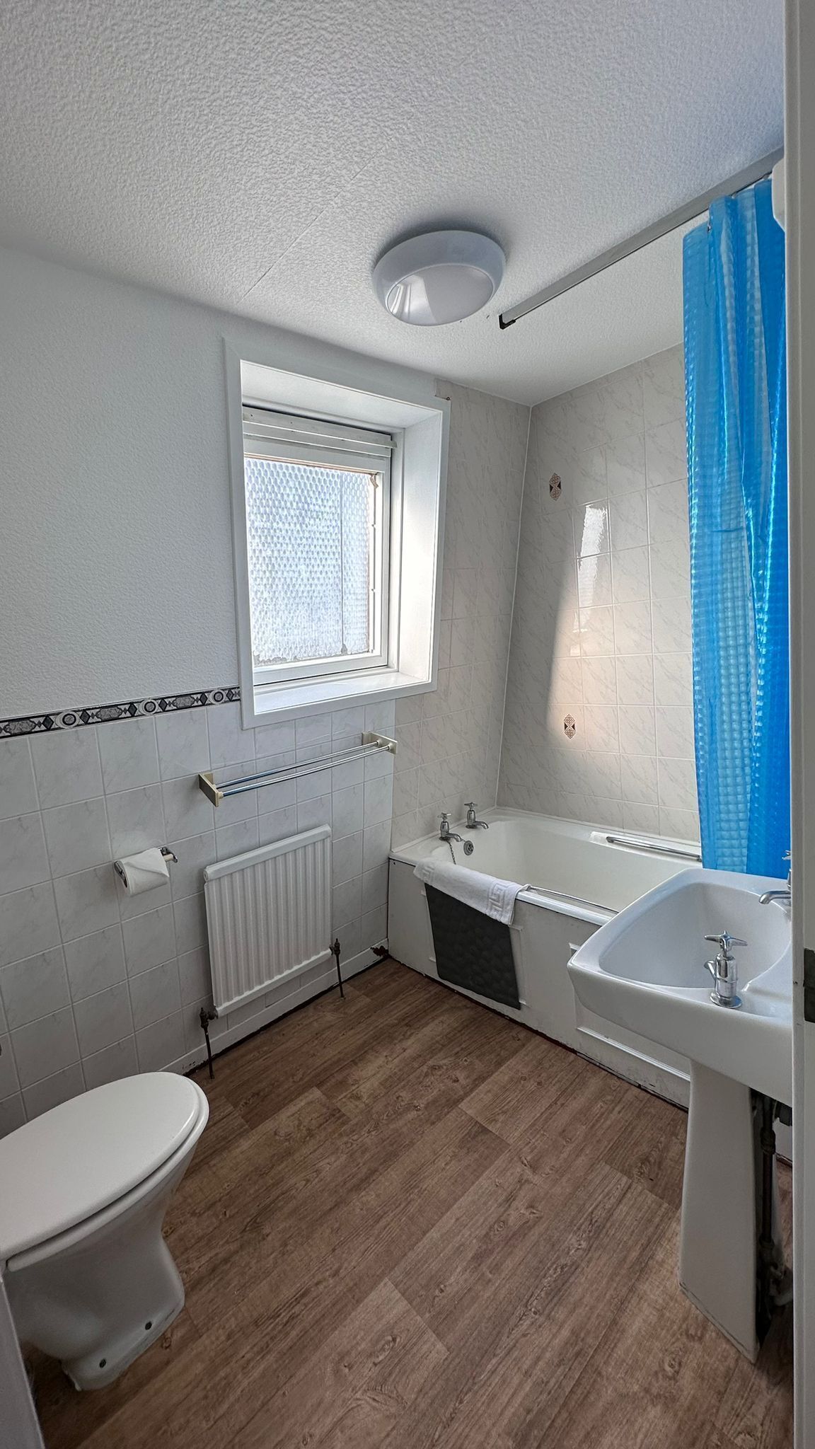 A bathroom with a toilet, a bathtub, a sink, and a window.
