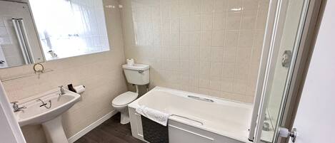 Un baño con lavamanos, inodoro, bañera y cabina de ducha de vidrio.