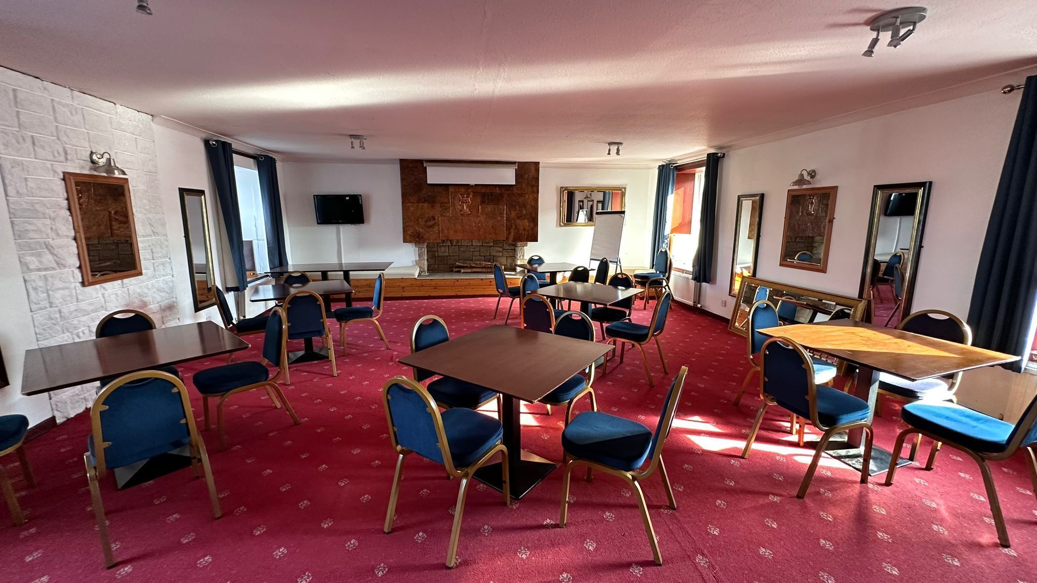 A conference room with tables and chairs, a fireplace, and a television.