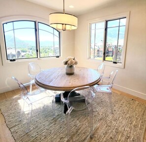 Enjoy meals at a round dining table surrounded by six chairs, with a beautiful view of the mountains.