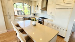 Una cocina moderna con armarios blancos, una isla central y un amplio ventanal que proporciona luz natural.